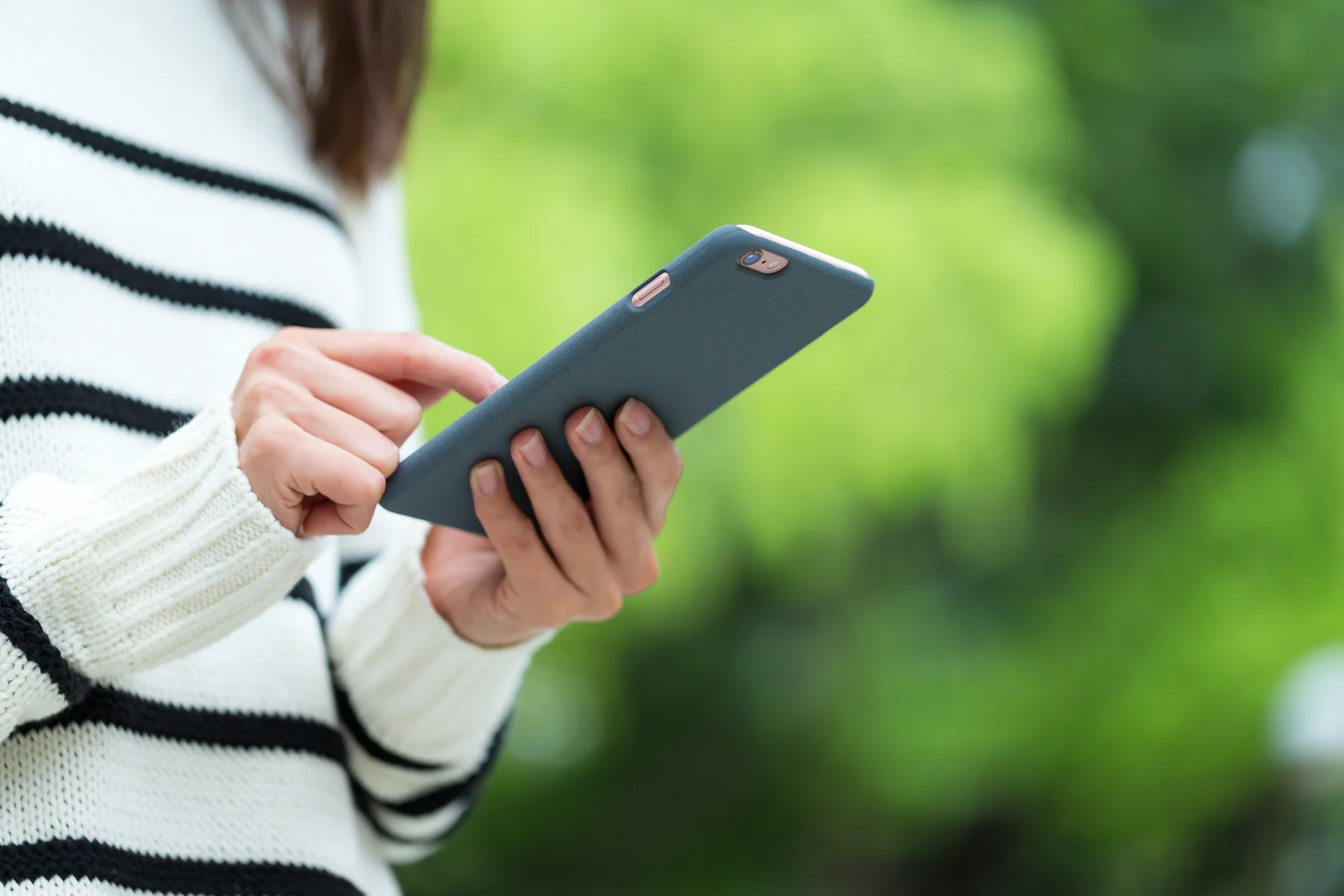 Vrouw in gestreepte trui met smartphone – Care for Women Haren, Groningen.