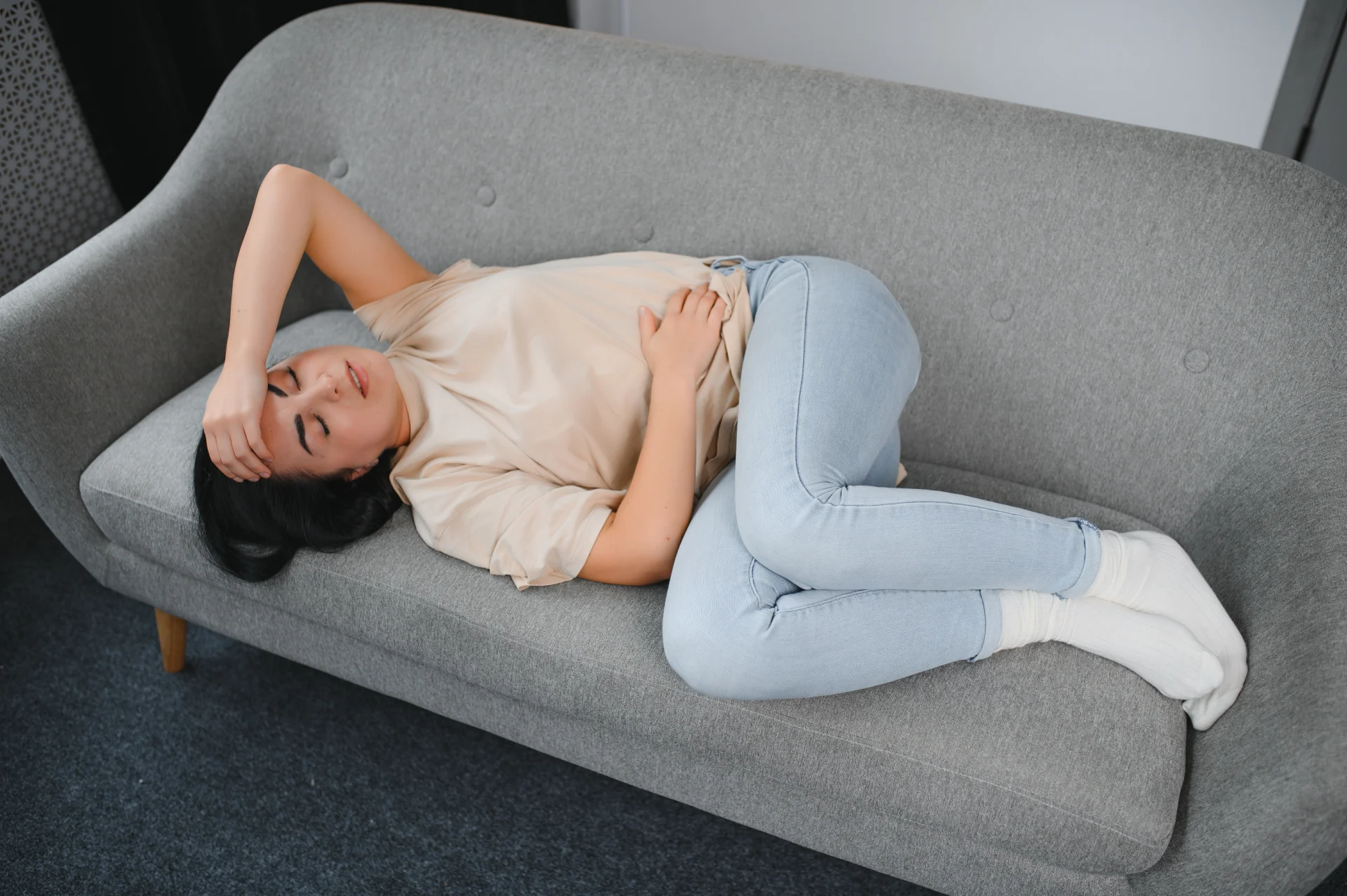 Vrouw op bank met pijnklachten – Care for Women Haren, Groningen.